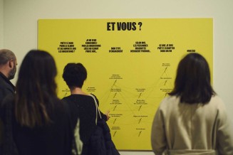 Photo d'ambiance du vernissage de l'exposition "Migrations & climat". Personnes devant un panneau avec l'inscirption : "Et vous ?"