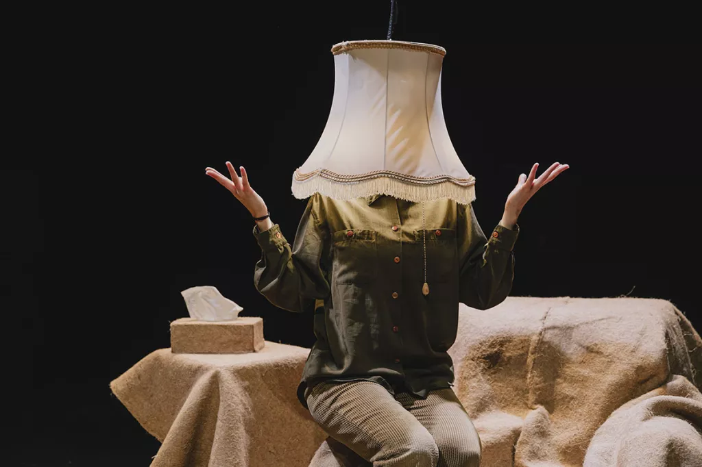 Image du spectacle "Sans faire de bruit" une personne qui a la tête dans un abat jour