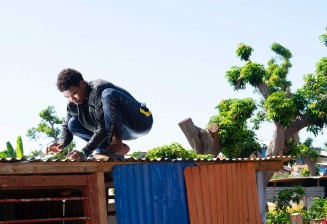 Laura Henno, "Un jeune cloue une tôle de son banga. Quartier informel de Barakani, Mayotte" © Laura Henno