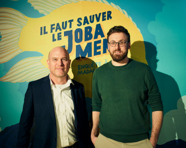 Brian Zimmerman et Charles-Edouard Fusari devant l'affiche de l'exposition Il faut sauver le Joba Mena : Enquête à Madagascra