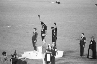Jeux Olympiques de Mexico (1968) – Sur le podium du 200m, les athlètes étasuniens Tommie Smith (médaille d’or) et John Carlos (médaille de bronze) lèvent un poing ganté de noir